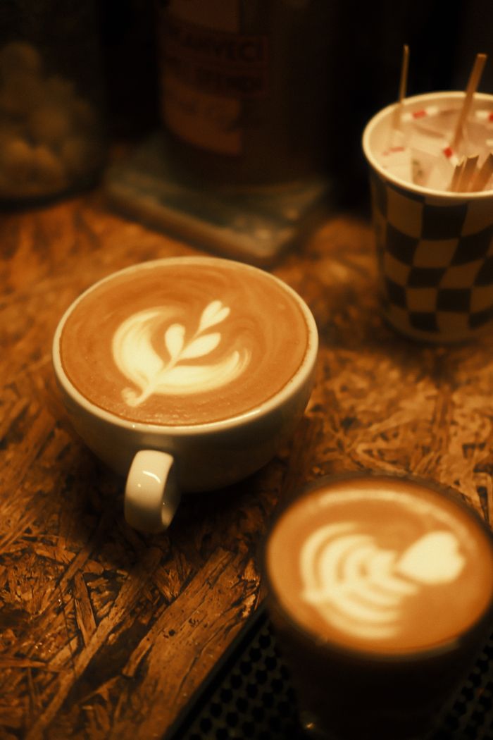 services-03 Warm-toned latte art featuring intricate designs in a cozy coffee shop setting.