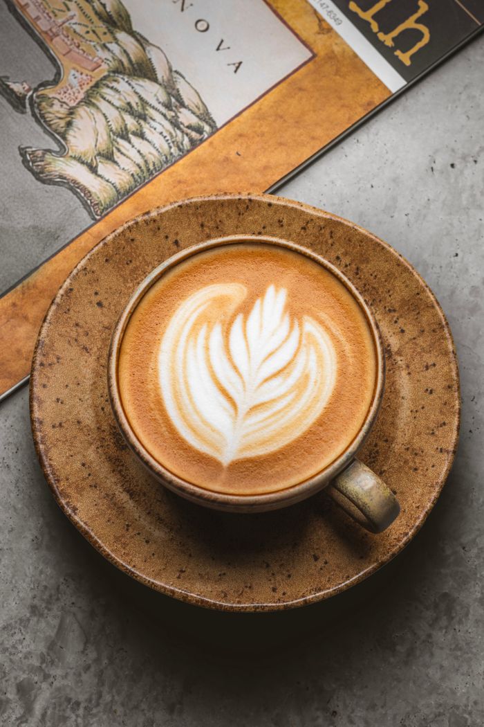 gallery-6 A beautifully crafted latte served in a rustic ceramic cup on a textured surface.