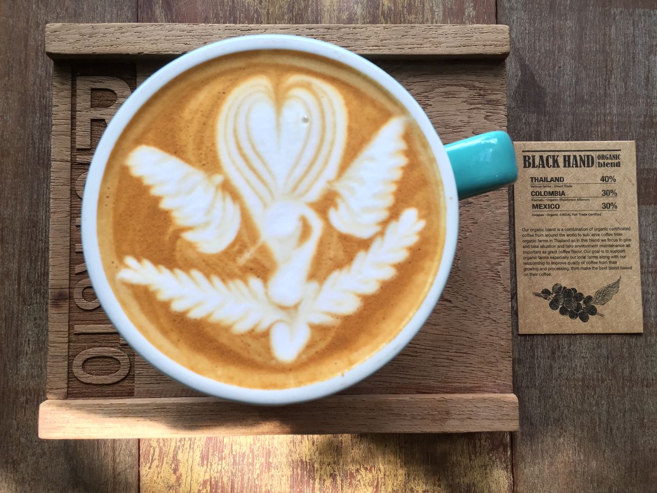 Close-up of a latte with detailed heart and swan latte art on a wooden table.