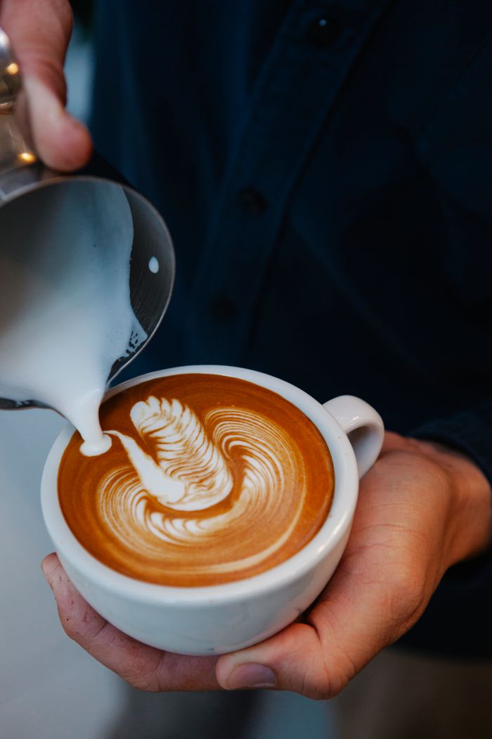services-img From above crop anonymous male barista pouring frothy milk into coffee cup and making latte art while working in cafe