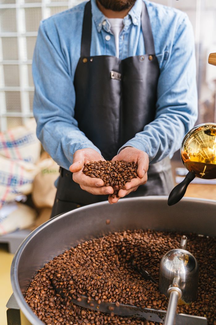 contact-img Master coffee roaster holding freshly roasted beans for quality inspection.